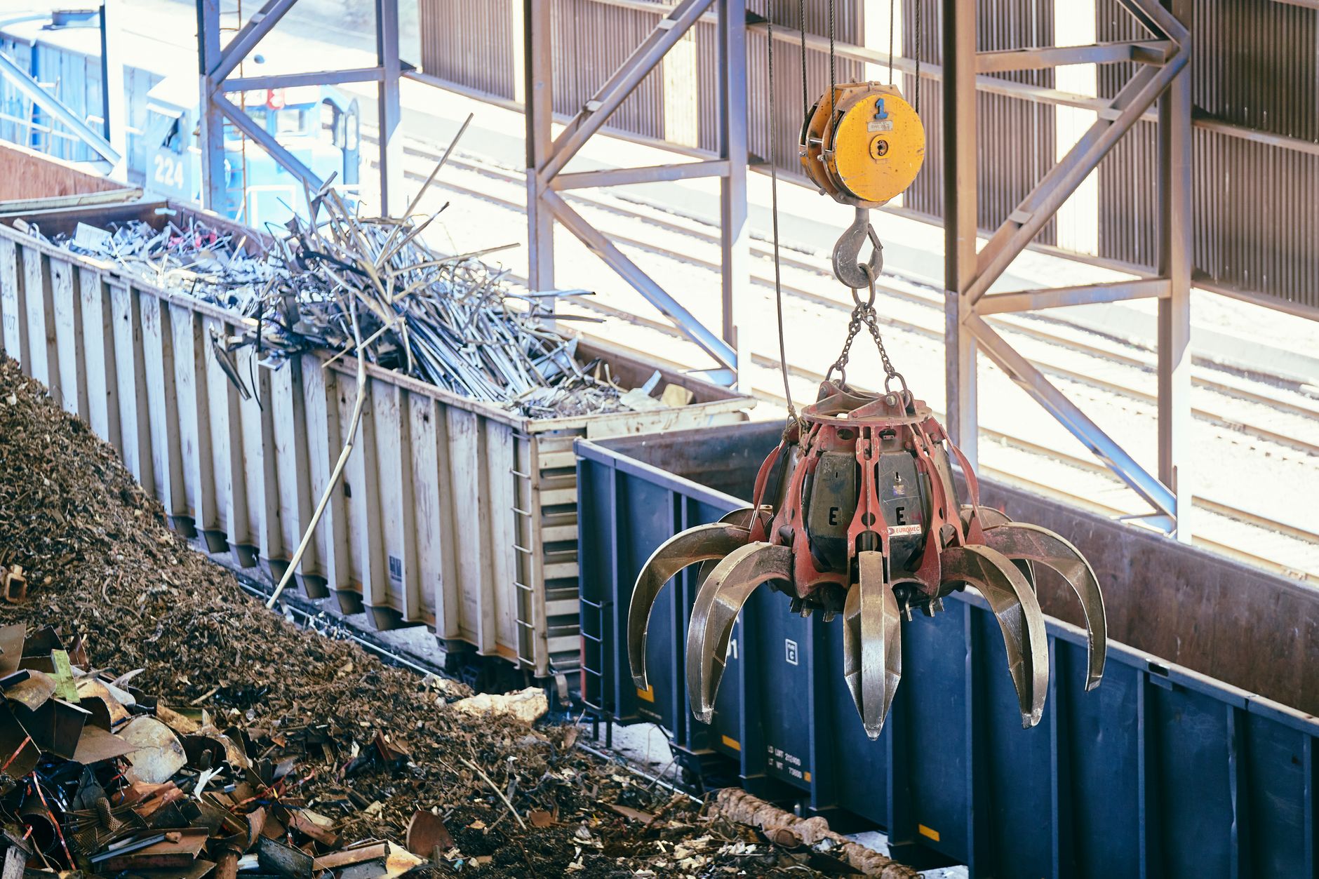 Overhead crane sorting scrap metal in an industrial recycling facility.