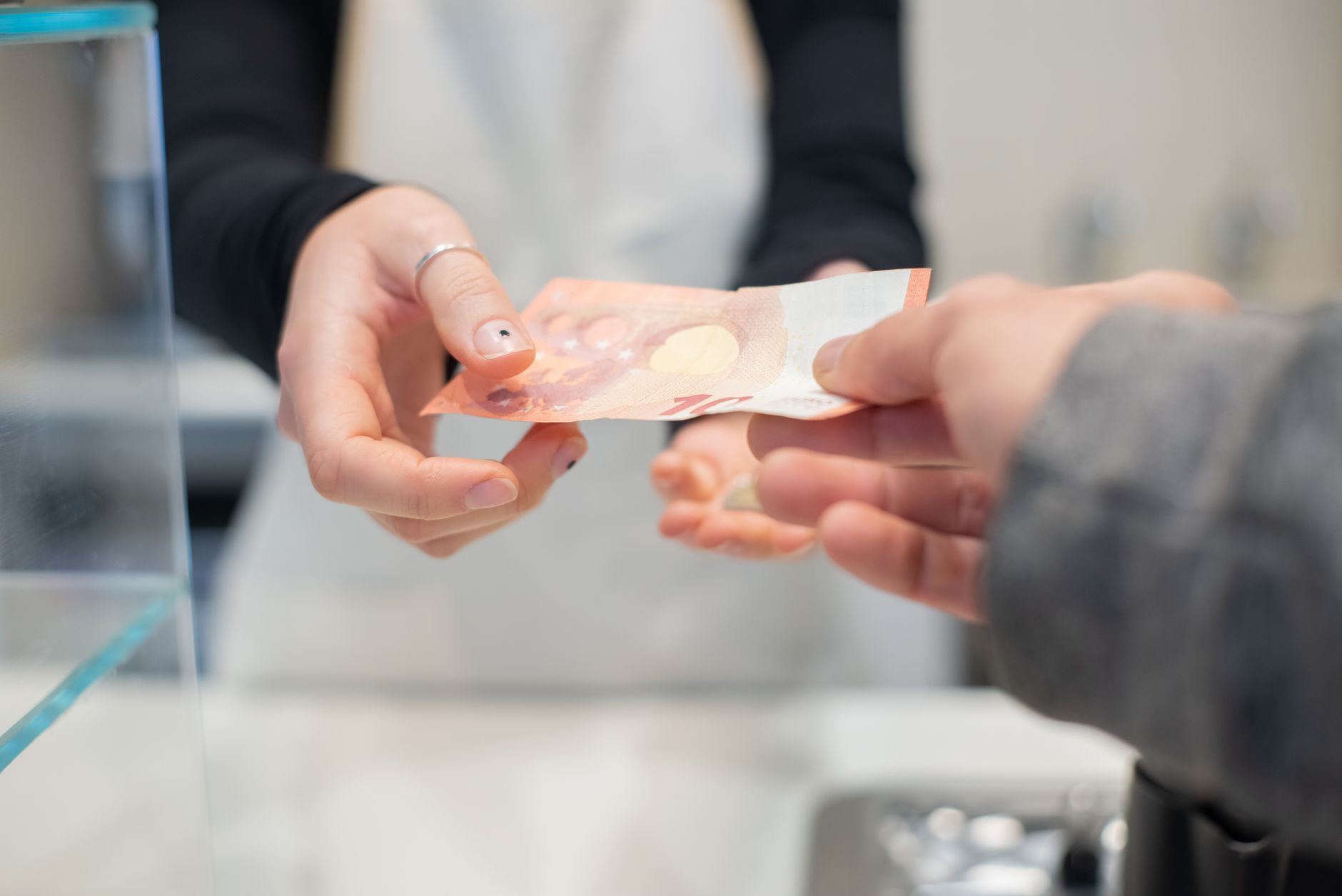 Close interaction of hands exchanging cash in a café setting. Business transaction detail.