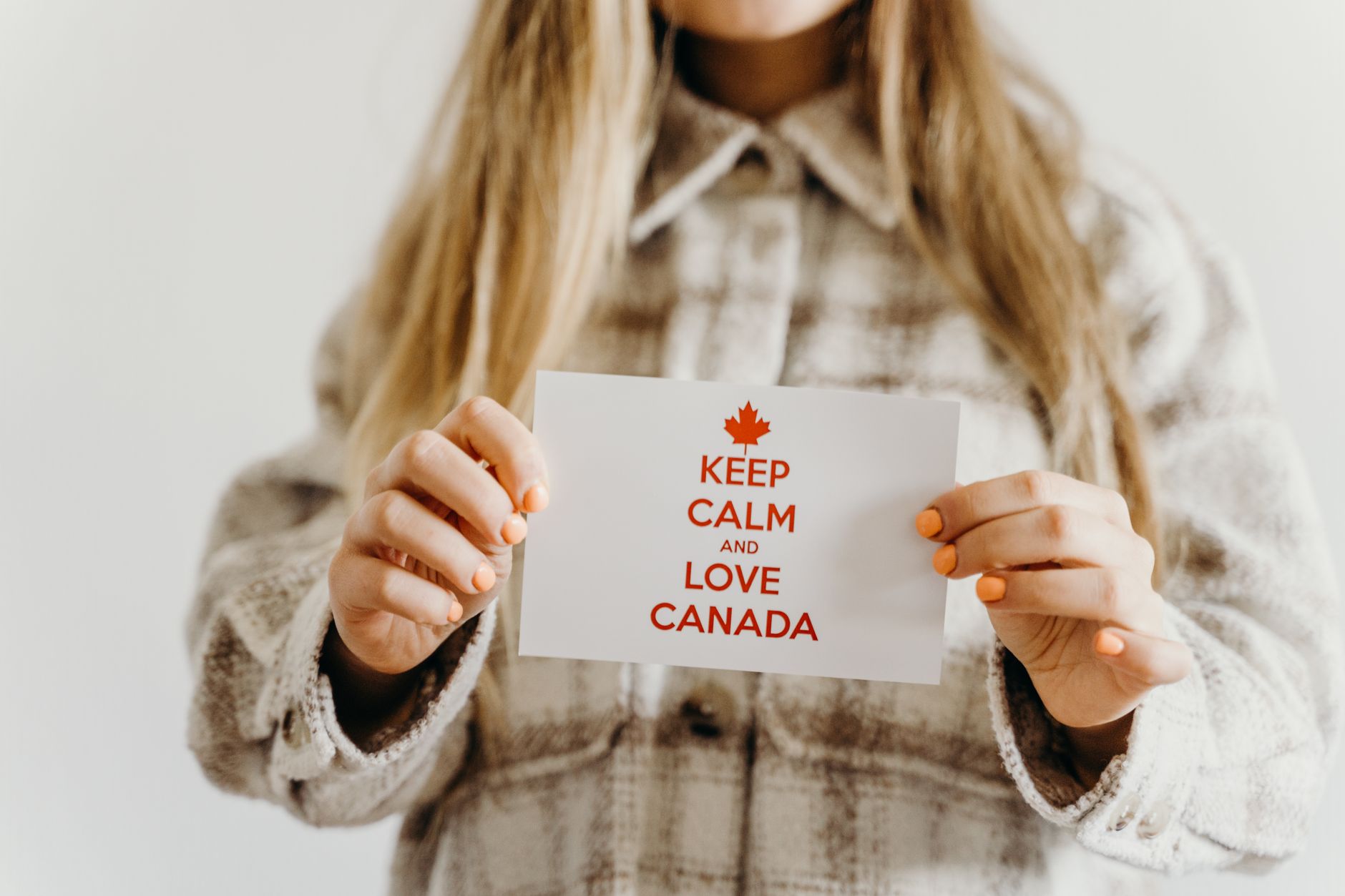 A close-up shot of a person holding a card with the message 'Keep Calm and Love Canada,' perfect for Canada Day celebrations.