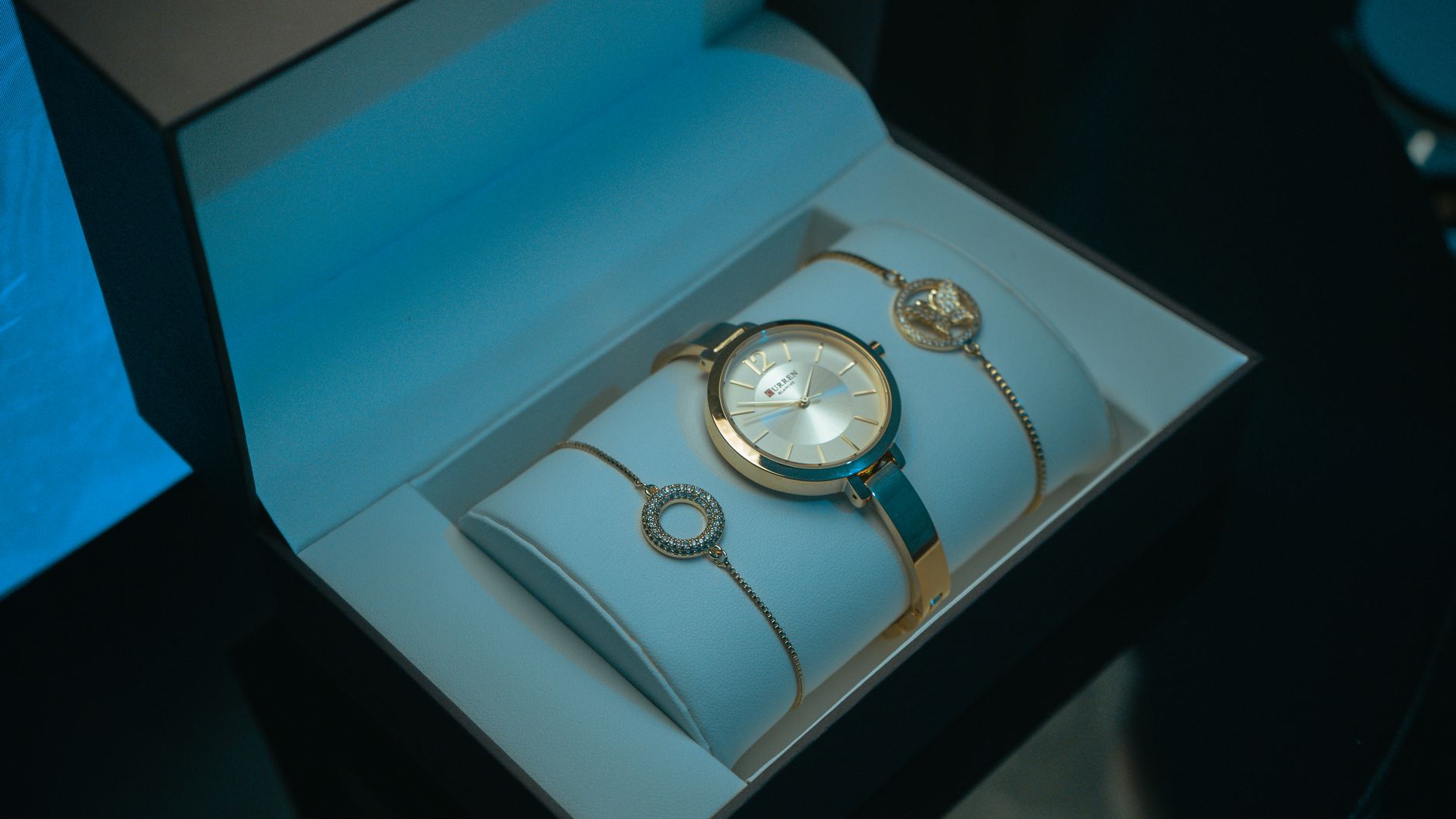 Close-up of a luxury gold watch and jewelry set in an elegant presentation box, showcasing glamour and wealth.